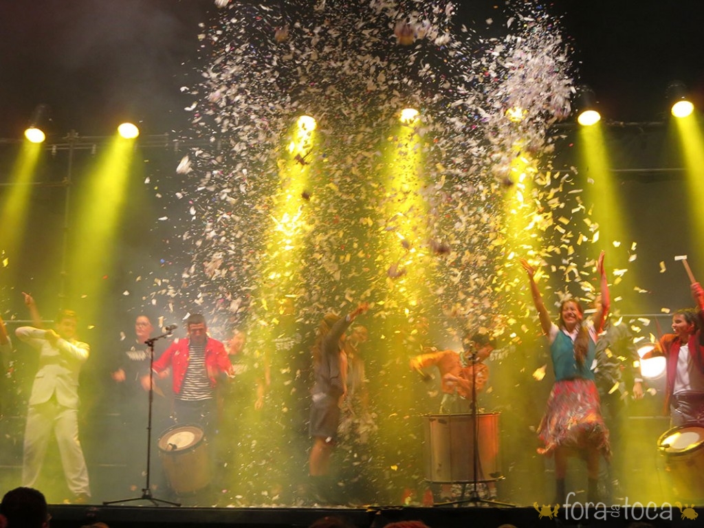 os atores tocam e dançam no palco no final do show em SP enquanto uma chuva de papel picado cai