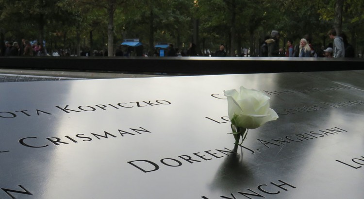detalhe de uma das placas de bronze com o nome das vítimas e uma rosa branca em homenagem